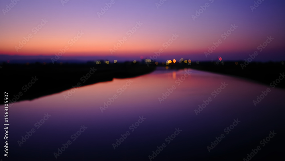 Fototapeta premium Blurred river reflects the colorful sunset sky at twilight