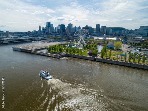 фотографія A boat cruises on the Saint Lawrence River in Montreal, Canada, offering tourists scenic views of the city skyline, La Grande Roue Ferris wheel, and waterfront park