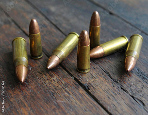 Close-up shot of several bullets scattered on a weathered wooden surface.