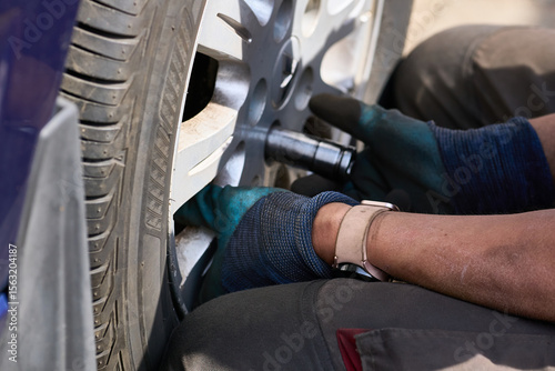 Repair car.Wheel mounting.Worker tightens nuts on wheel