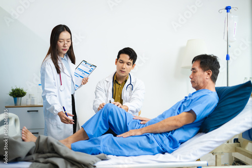 Doctor and nurse assess senior patient’s leg injury in hospital, using tablet x-ray to explain diagnosis and care.