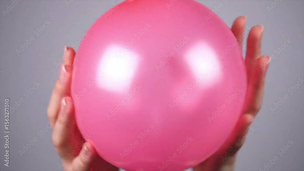 A shiny pink balloon is deflated in front of a gray background, creating a distinctive and audible sound effect. This audio element is great for sound design, special effects