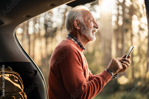 Senior Man Enjoying Outdoor Smartphone Experience in Forest at Sunset