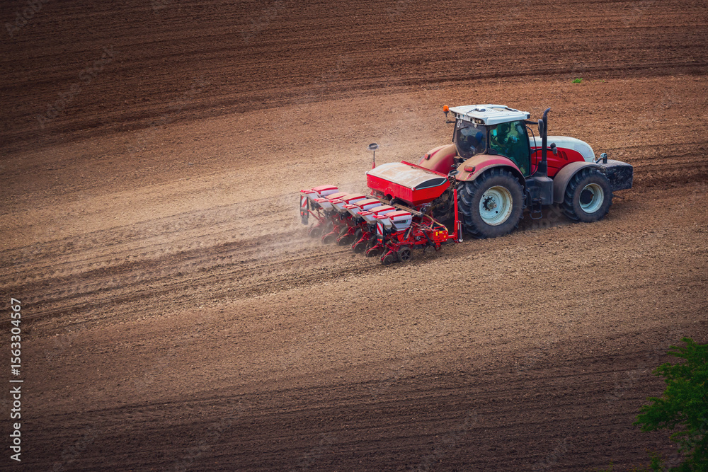 Obraz premium Farmer in tractor preparing farmland with seedbed for the next year, tractor seeding crops at field aerial panorama landscape