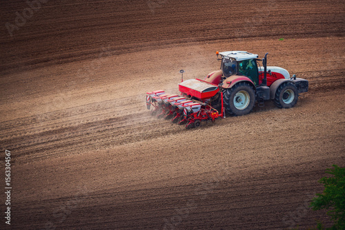 Farmer in tractor preparing farmland with seedbed for the next year, tractor seeding crops at field aerial panorama landscape