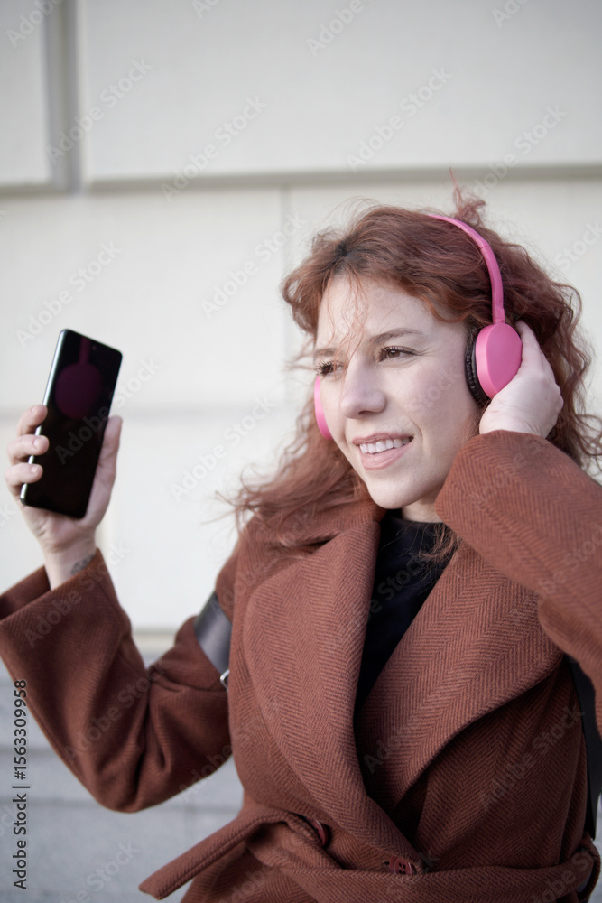 Naklejka premium Young woman enjoying music with pink headphones