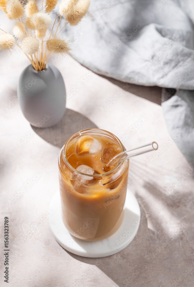 Ice latte coffee in a glass with milk on a light background with dry bouquet flowers Ice latte coffee in a glass with milk on a light background with dry bouquet flowers