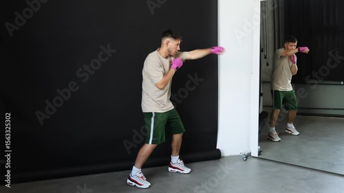 Young athlete practices boxing techniques in a training studio with a mirror