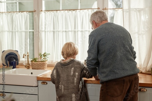 Foto Senior Caucasian man standing beside child at kitchen counter in village home, b