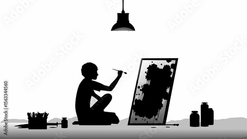 Silhouette of a young artist painting a canvas with a brush under a hanging lamp in a studio space