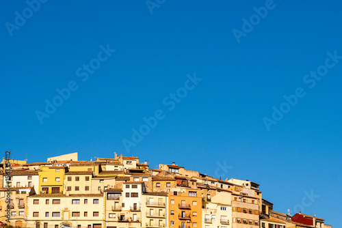 Colorful urban skyline with densely packed rooftops under intense blue sky, capturing Mediterranean architecture, minimal urban pattern, and abstract geometric cityscape elements