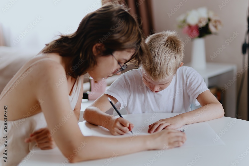 Young mother helps her hard-of-hearing son with schoolwork at home. A natural, heartfelt moment of inclusion, care, and rehabilitation, highlighting love, support, and everyday learning Young mother helps her hard-of-hearing son with schoolwork at home. A natural, heartfelt moment of inclusion, care, and rehabilitation, highlighting love, support, and everyday learning