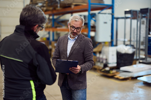 Wall Mural Manager Discussing Warehouse Operations with Worker in Industrial Setting
