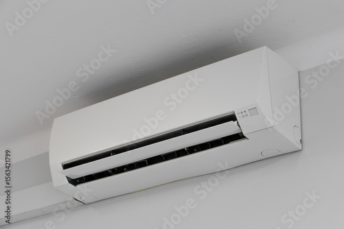 Air conditioning hanging high up from the ceiling on a white wall, damaged air conditioner AC
