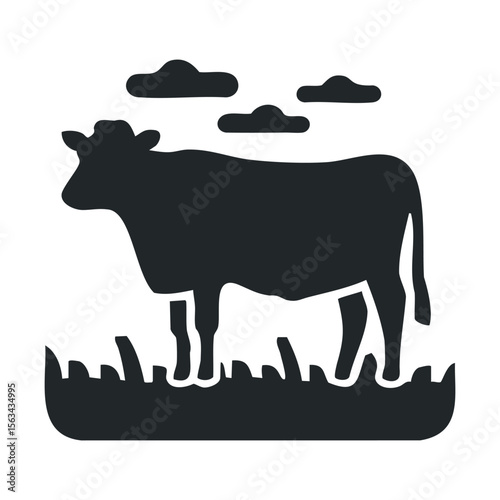 Silhouette of a cow in a field with clouds