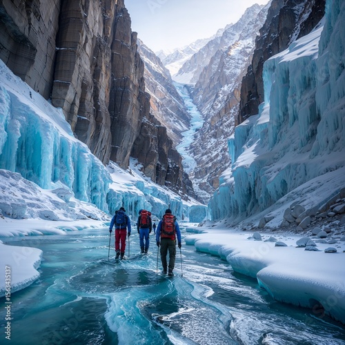 Trekkers walking over frozen Zanskar river with icy cliffs and waterfalls all around