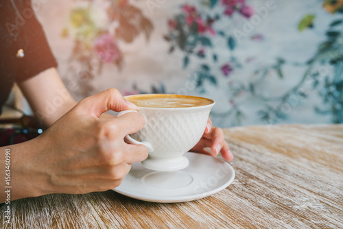 Coffee in cafe. Elegant Ceramic Cup of Coffee Being Held by Woman with Beautiful Floral Background in Cozy Cafe Setting