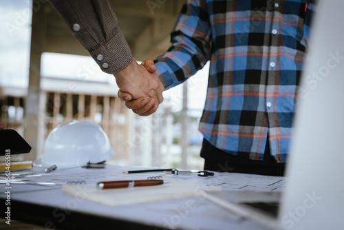 Photos Two builders shaking hands at a construction site, representing a successful agreement and partnership built on trust, cooperation, and a shared goal of developing and growing real estate