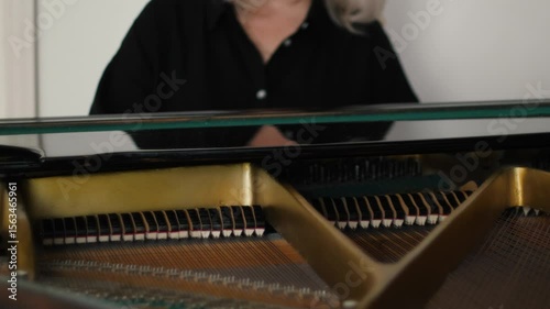 female pianist or music teacher plays the piano, inside the instrument dampers move up and down on the strings, concept music education or rehearsal before a performance