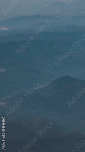 View from above on the horizon and high mountains with snow and clouds. Flight in the sky on a large passenger liner during travel and vacation. Airplane window and wing in the air
