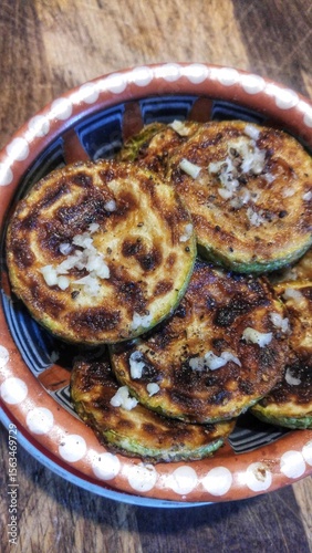 Grilled zucchini slices with garlic and pepper in rustic bowl.