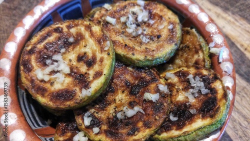 Grilled zucchini slices with garlic and pepper in rustic bowl.