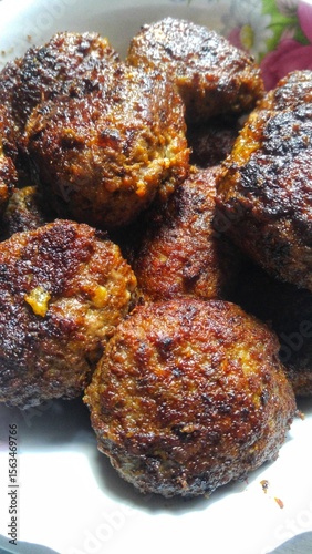 Crispy homemade meatballs with golden crust in white plate.