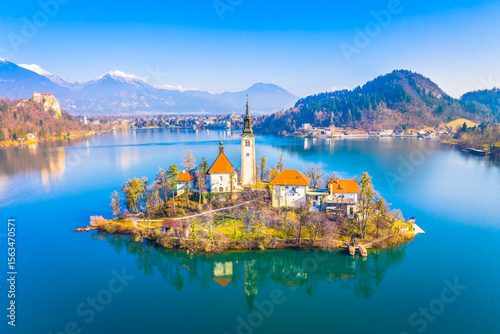 Aerial view of the fairytale island on Lake Bled, Slovenia, featuring the picturesque church surrounded by emerald alpine waters and mountainous backdrops that define this iconic resort