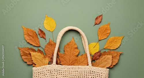 Jute tote bag with autumn leaves on green background.
