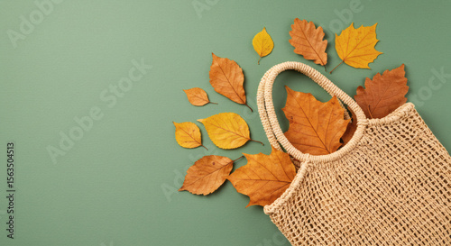 Top view of a jute shopping bag arranged with scattered dried leaves.