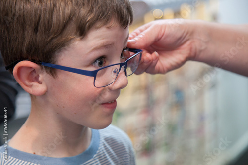 Young boy trying on different frames for new glasses