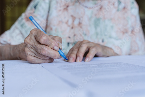 Senior woman signing insurance papers at home photo