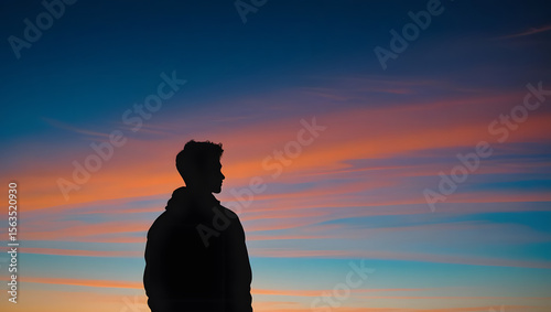 Solitary Figure Silhouetted Against Vibrant Sunset Sky on Hilltop