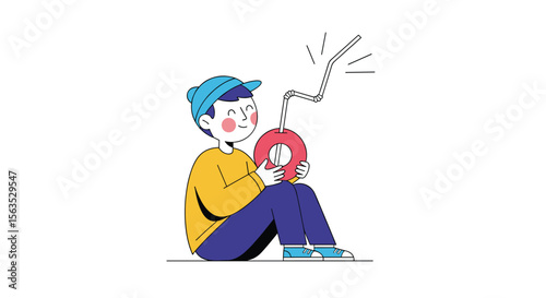 A young boy wearing a blue baseball cap is sitting cross-legged on the ground enjoying a drink through a straw from a round object