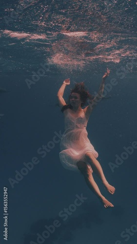 Beautiful young woman swimming underwater with dolphins in pristine blue ocean water, amazing snorkeling adventure. Armature freediver girl diving in red sea with bottlenose dolphins. Travel concept