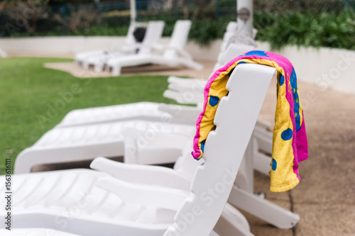 Resort sun lounges by the pool with towel draped over the back