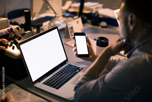 Man looking at blank phone screen at night in dark office workspace