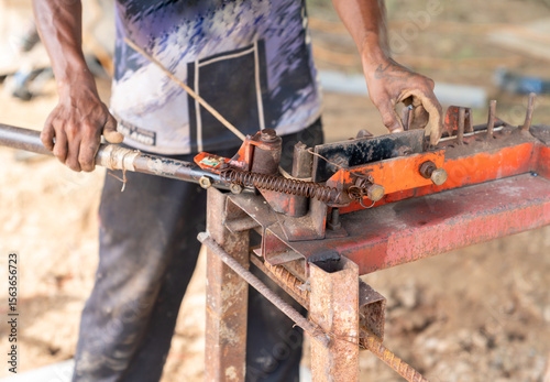 The workers are bending rebar at the construction site.