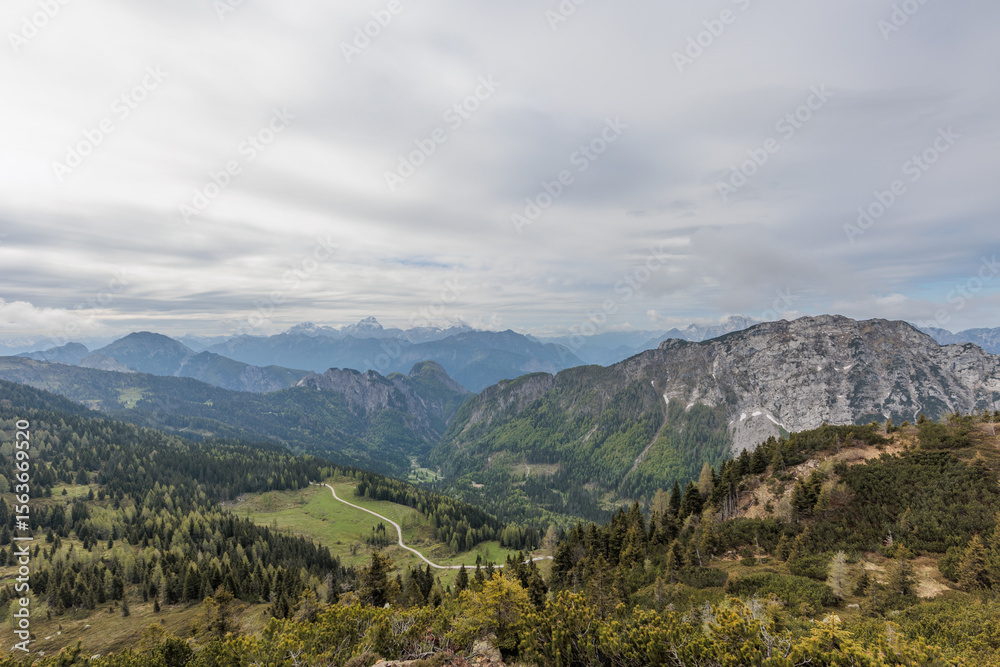 Naklejka premium ampia vista panoramica dalla cima di un monte vicino a Passo Pramollo, tra Italia ed Austria, di mattina, in primavera, con cielo nuvoloso