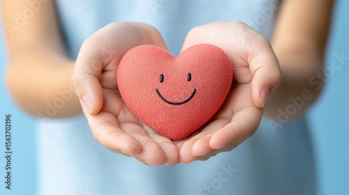Hands Holding Red Heart with Smile Face, Expression of Love and Happiness, Gentle Caring Gesture, Soft Background for Positive Emotions and Relationships