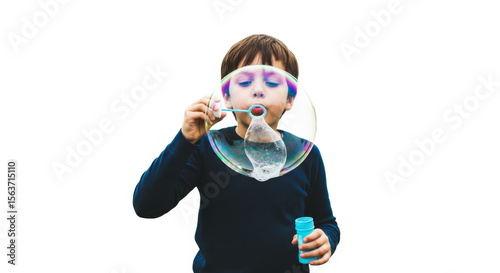 A boy blowing a large soap bubble with a wand against a plain white background in an outdoor setting