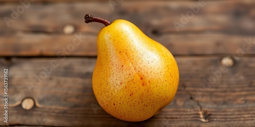 A single, perfectly ripe pear, exhibiting a rich golden-brown hue and slight blush, sits on a rustic wooden surface, pear,  orchard