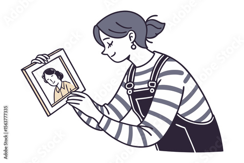 Joyful young woman with a smile looks at a framed photograph of a smiling woman reminiscing fondly