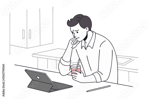 A thoughtful young man sits at a counter holding a drink and contemplating his tablet with kitchen cabinets in the background