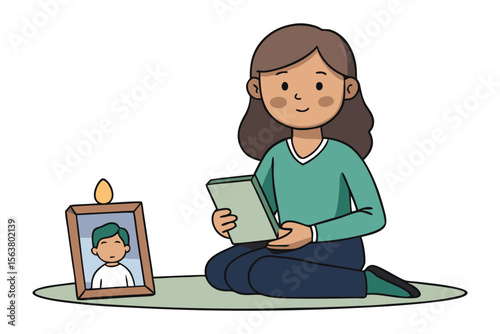 A person sits on a mat holding a book remembering a loved one with a framed photo and a lit candle nearby