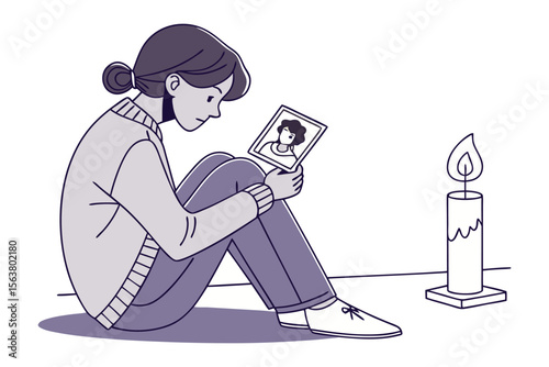 A person sits alone holding a photograph of another person with a lit candle nearby symbolizing remembrance and grief