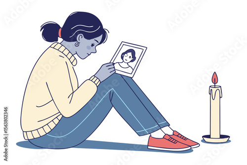 A young woman sits in contemplation holding a photograph and gazing at a lit candle evoking feelings of remembrance and solitude
