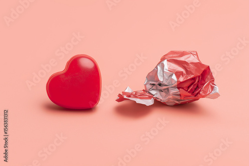 Heart-shaped candy next to crumpled candy wrapper