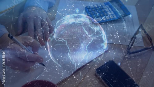 Hand placing notepad causing rotating globe while writing notes, using calculator for data analysis