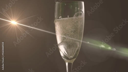 Horizontal beam glancing off champagne flute illuminating bubbles creating green flare artifacts